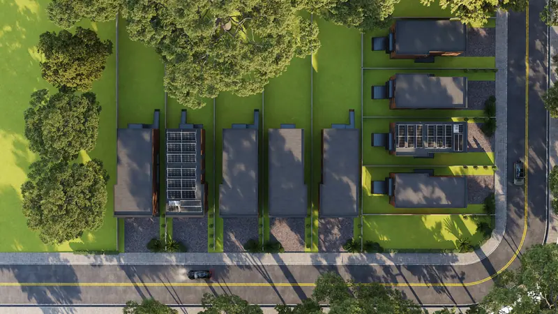 Aerial view of a row of houses with landscaping on a green site beside a road